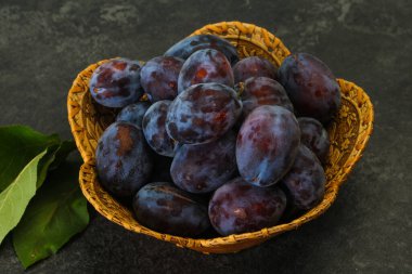 Olgun erik yığını sepetin içinde yapraklarla