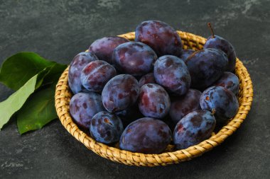 Olgun erik yığını sepetin içinde yapraklarla