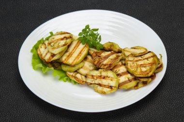 Izgara patlıcan dilimleri fesleğen ve salata yaprakları servis edilir.