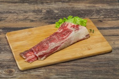 Tahtanın üzerinde çiğ domuz pastırması salata ve kekik servis edildi.