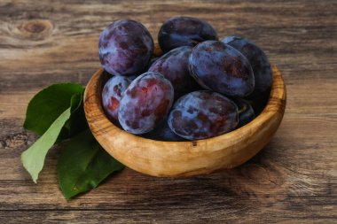 Olgun erik yığını sepetin içinde yapraklarla