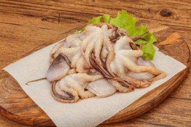 Çiğ deniz ürünleri - ahtapot tahtada pişirmek için.