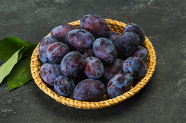 Olgun erik yığını sepetin içinde yapraklarla