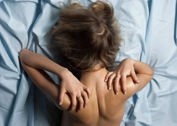 Close-up back view cansado feminino massageando sua dolorosa no fundo azul. Dor nas costas e na coluna . — Fotografia de Stock