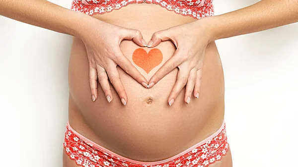 Detailní záběr roztomilé těhotné břicho s červeným srdcem. — Stock fotografie