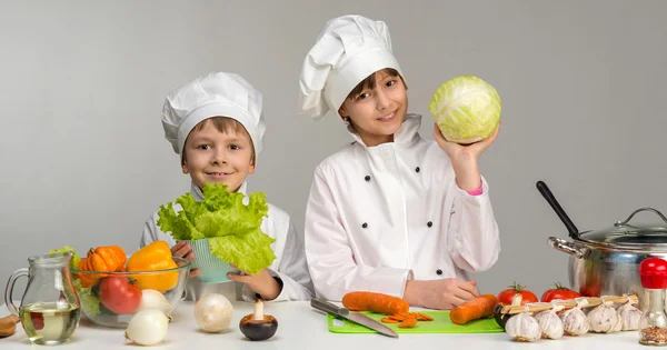 Due bambini cuochi sorridenti vicino al tavolo — Foto Stock