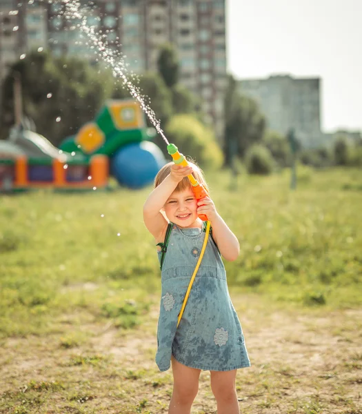 Malá holčička hraje vodní pistole — Stock fotografie