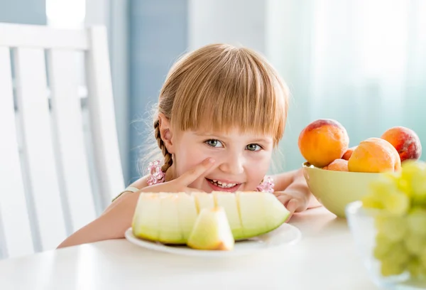 Menina com frutas na mesa — Fotografia de Stock