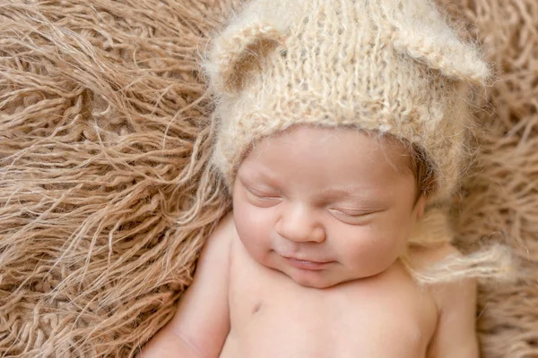 Adormecido sorrindo bebê recém-nascido em chapéu — Fotografia de Stock