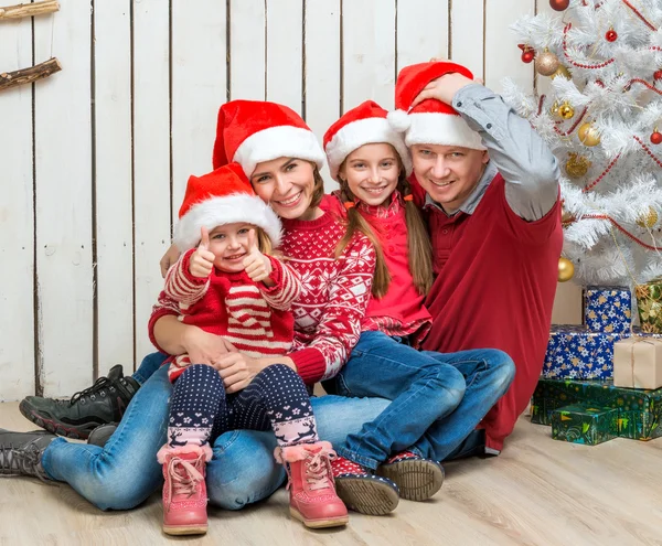 Familia en los sombreros de Santa cerca del árbol de Navidad — Foto de Stock