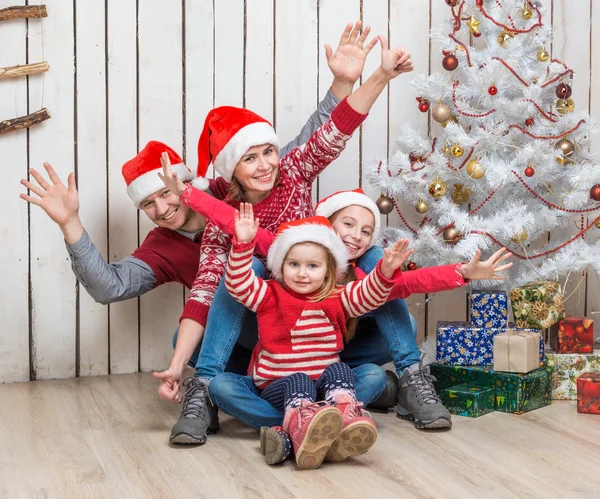 Familia en los sombreros de Santa cerca del árbol de Navidad —  Fotos de Stock