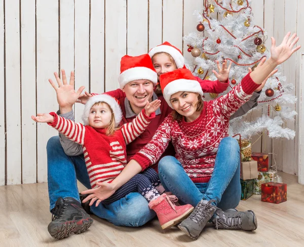 Familia en los sombreros de Santa cerca del árbol de Navidad — Foto de Stock