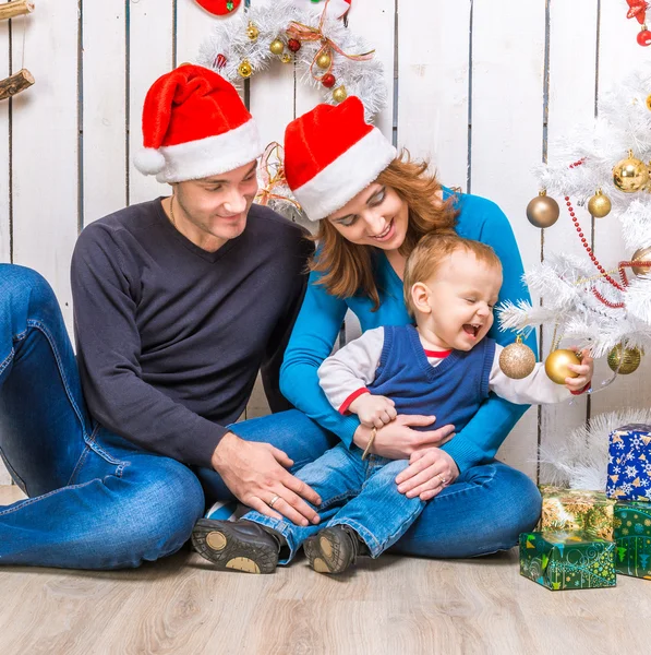 Familie in rode hoeden in de buurt van de kerstboom — Stockfoto