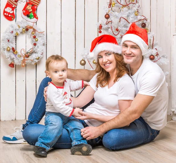 Familie in rode hoeden in de buurt van de kerstboom — Stockfoto