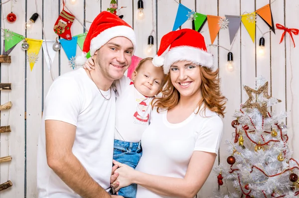 Familie in rode hoeden in de buurt van de kerstboom — Stockfoto