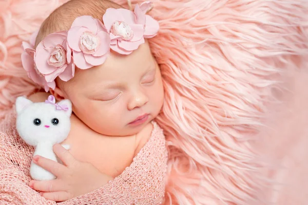 Lovely newborn girl holding toy on pink fluffy blanket — Stock Photo, Image