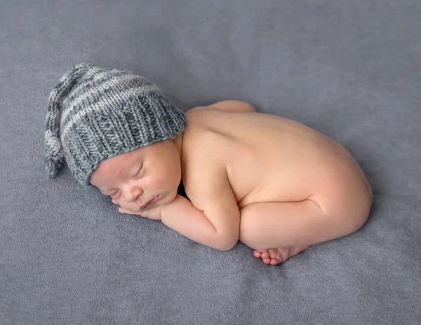 Голый новорожденный в шляпе спит на одеяле — стоковое фото