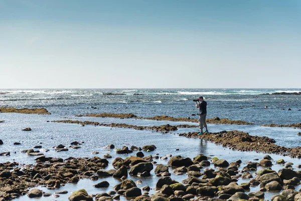 Turista tomando fotos en la costa pedregosa de Canarias —  Fotos de Stock