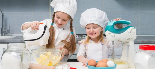 Duas meninas em uniforme de chef com ingredientes na mesa — Fotografia de Stock