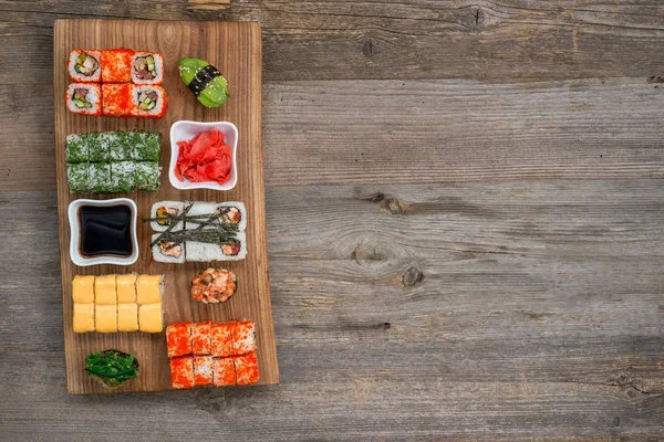 Набор суши и рулонов с палочками для еды на деревянном столе — стоковое фото