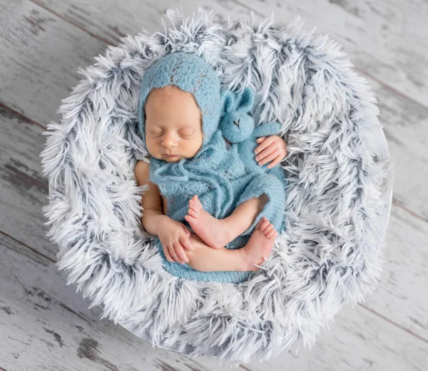 Härlig spädbarn i hatt och jumpsuit sover på rund säng — Stockfoto