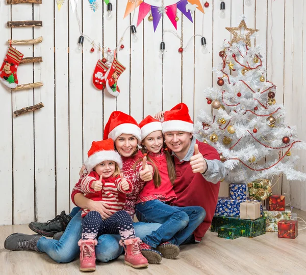 Velká rodina v červené santa klobouky u vánočního stromu — Stock fotografie