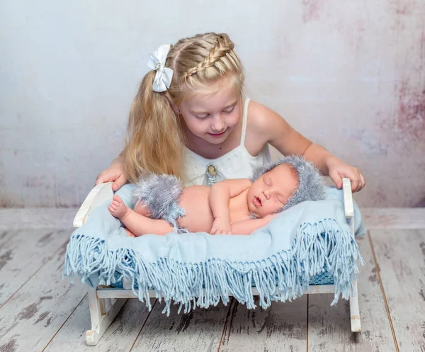 Recém-nascido adormecido em pequena cama e sua irmã — Fotografia de Stock