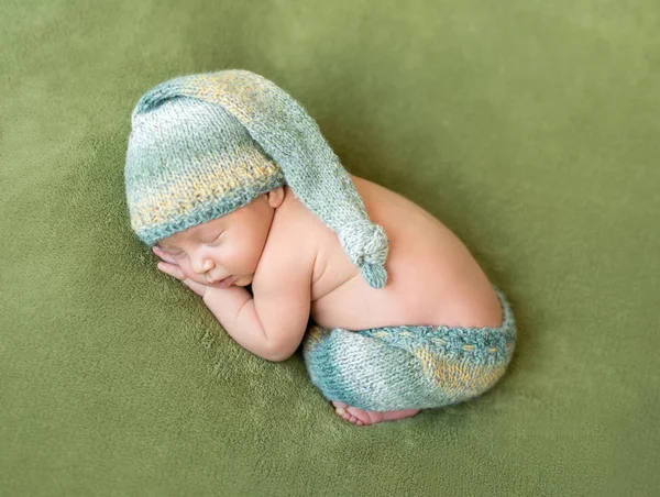 Adorável recém-nascido em chapéu e calcinha dorme enrolado — Fotografia de Stock