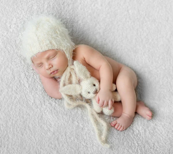 Nu dormindo bebê no chapéu com brinquedo no cobertor branco — Fotografia de Stock