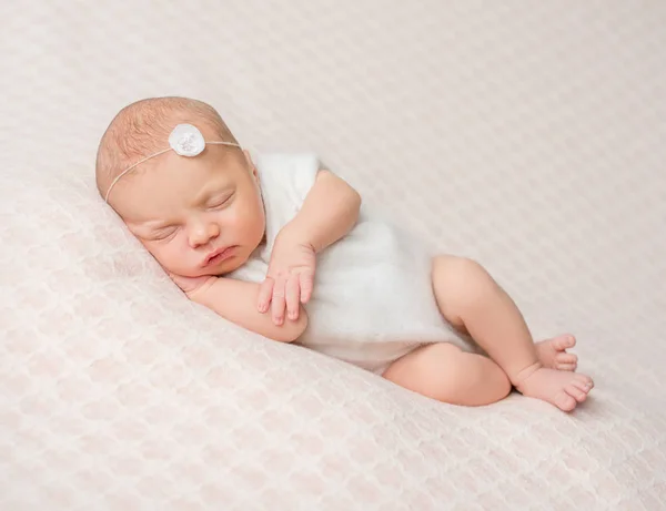 Sovande nyfödda flicka med blomma på hennes pannband — Stockfoto
