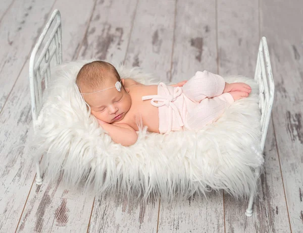 Newborn sleeping baby holding toy on cute little bed — Stock Photo, Image