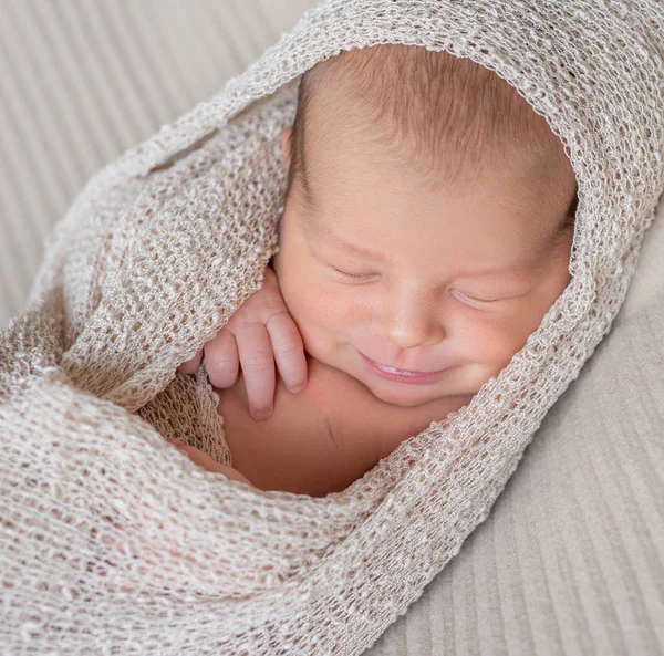 Wrapped newborn baby sleeping with smile — Stock Photo, Image
