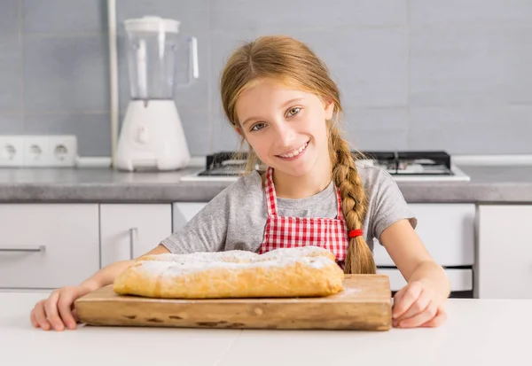 Mooie litte meisje met gebakken appel strudel op tafel — Stockfoto