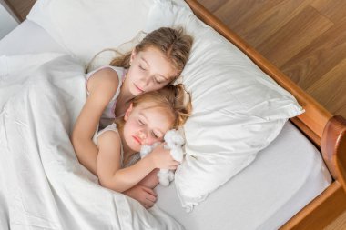 iki küçük kız yatakta sarılma