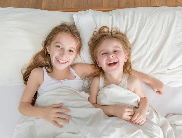 Zwei kleine hübsche Schwestern im weißen Bett — Stockfoto