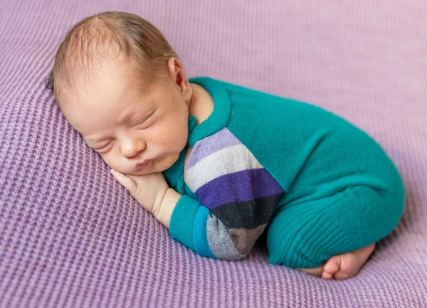 Cute newborn in warm overalls sleeping on blanket — Stock Photo, Image