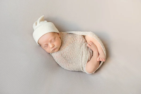 Wrapped sleeping newborn baby in white hat — Stock Photo, Image