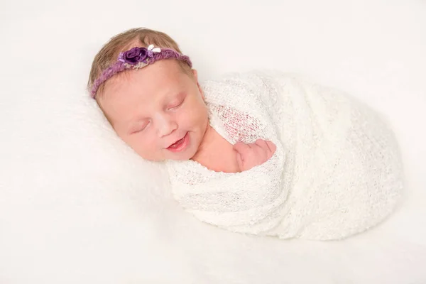 Cute newborn in headband with flowers smiling asleep — Stock Photo, Image
