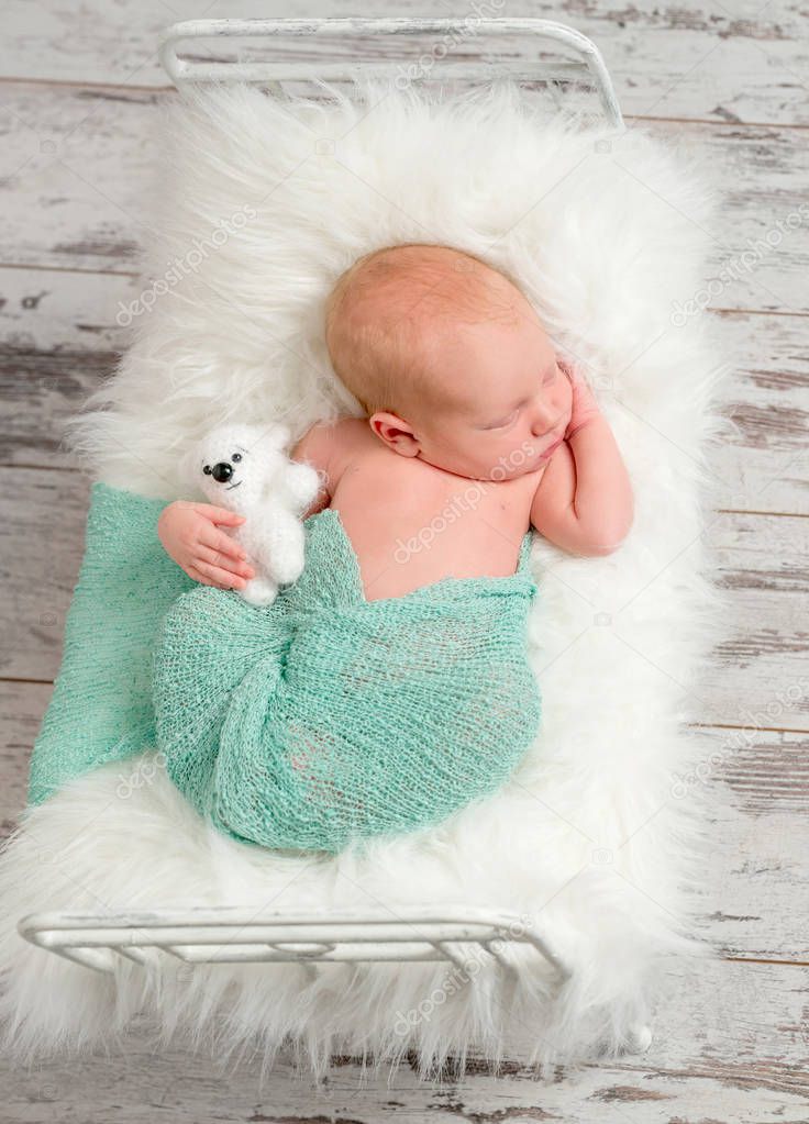 newborn sleeping on cot with white soft blanket