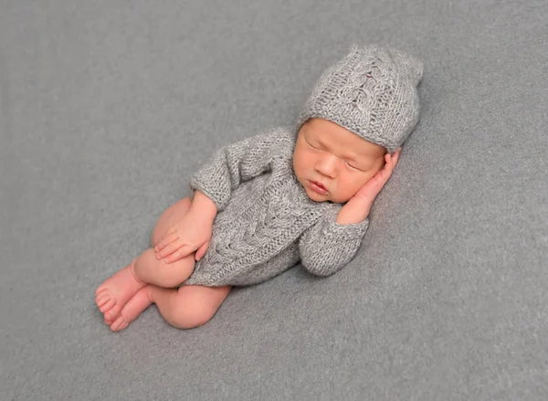 Spädbarn sover i en stickad outfit — Stockfoto