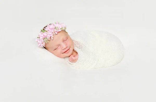 Nyfödd baby swaddled i vit blöja leende sover — Stockfoto