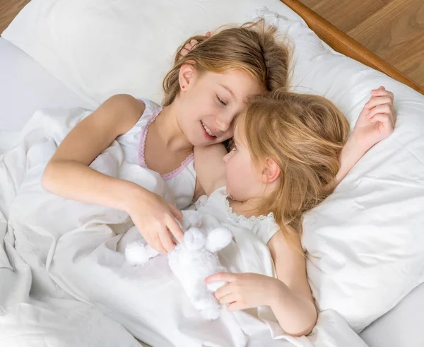 Twee zusjes knuffelen in bed — Stockfoto
