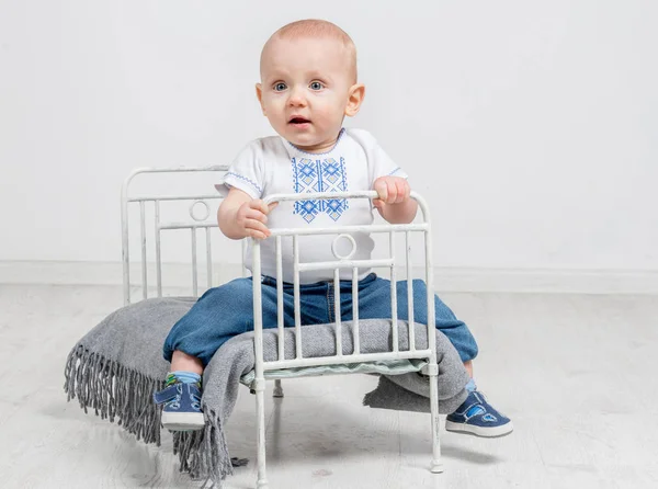 Söt nyfiken baby sitter på en liten säng — Stockfoto