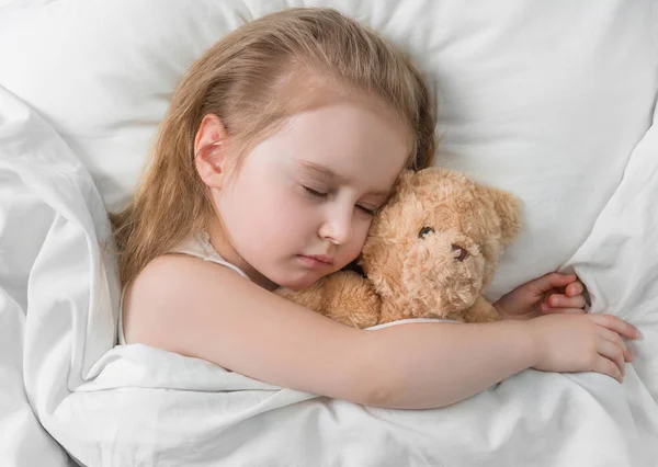 Kind schläft mit einem niedlichen Teddybär — Stockfoto