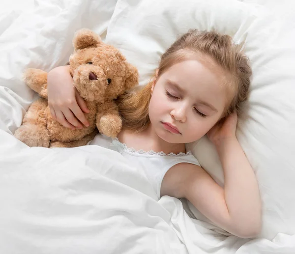 Kind schläft mit einem niedlichen Teddybär — Stockfoto