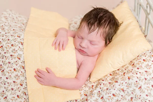 Baby slapen in bed met kleurrijke bladen — Stockfoto