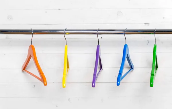 Multicolored hangers near the white brick wall — Stock Photo, Image