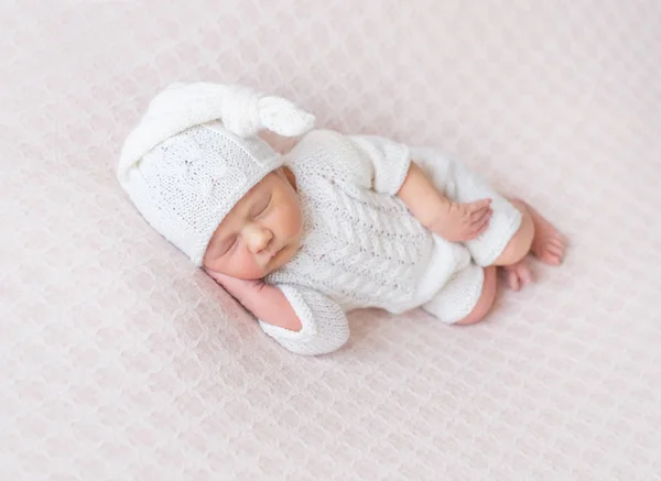 Baby som sover på sidan, i stickad dräkt — Stockfoto