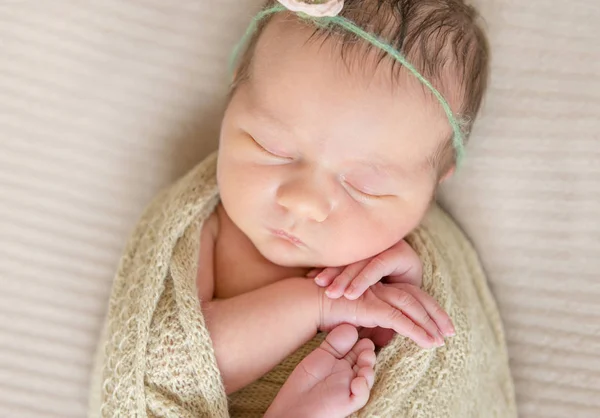 Enfant dans un bandeau fleuri dormant enveloppé, vue de dessus — Photo