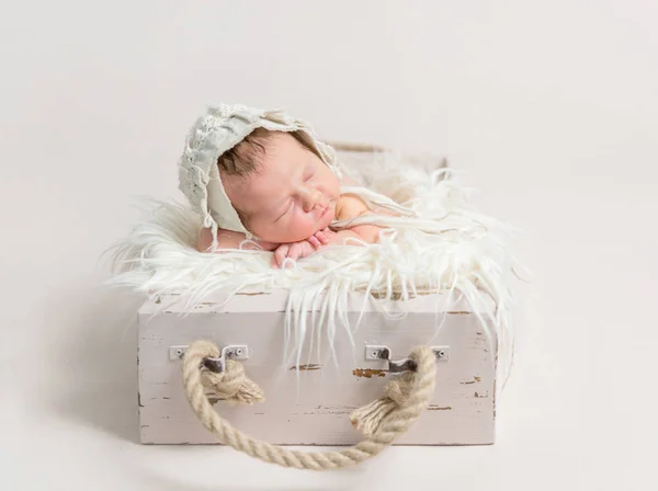 Criança dormindo em caixa rústica, usando chapéu — Fotografia de Stock